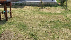 Ein Haus mit überdachter Terrasse, Rasen und Garten.