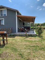 Una casa con porche cubierto, césped y jardín.