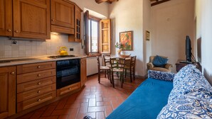 A kitchen with wooden cabinets, a stove, and a dining area with chairs and a table. - Farmhouse "Fattoria" with Shared Pool, Private Garden & Wi-Fi (Laterina)