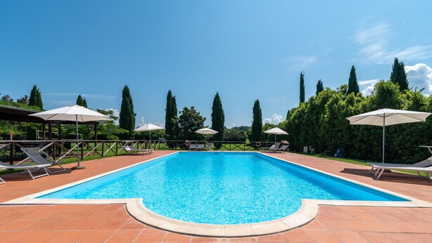A rectangular swimming pool with a tiled deck, surrounded by lounge chairs and umbrellas. - Farmhouse "Fattoria" with Shared Pool, Private Garden & Wi-Fi (Laterina)