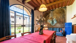 A dining area with a table set for two, a chandelier, and a mural on the wall. - Farmhouse 'Mulino ' with Shared Pool, Terrace & Wi-Fi (Laterina)