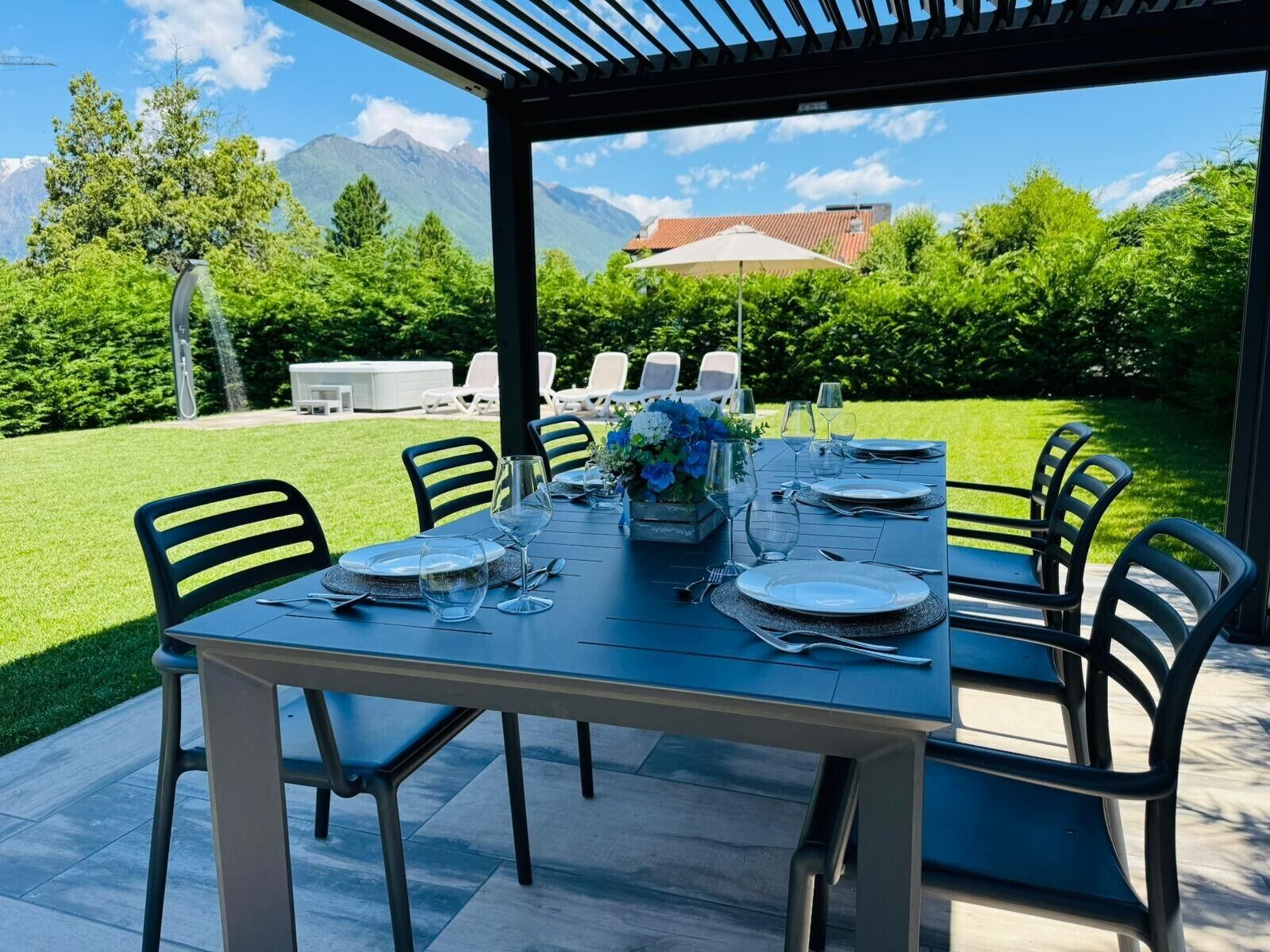 A dining table set for six with chairs, a view of mountains, and a patio area.