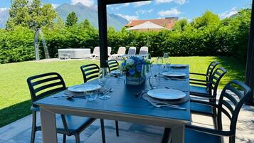 A dining table set for six with chairs, a view of mountains, and a patio area.