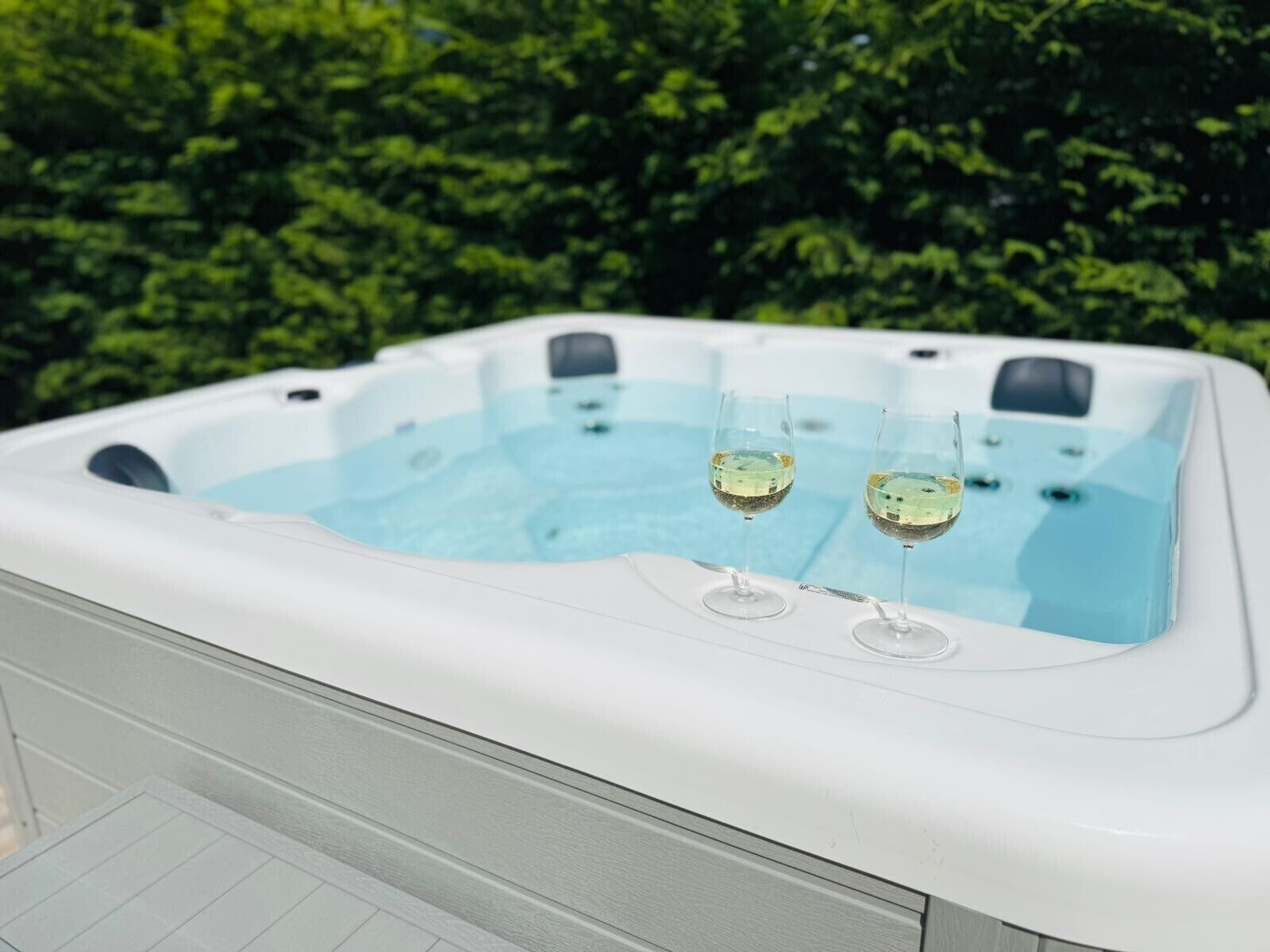 A hot tub with two glasses of wine.