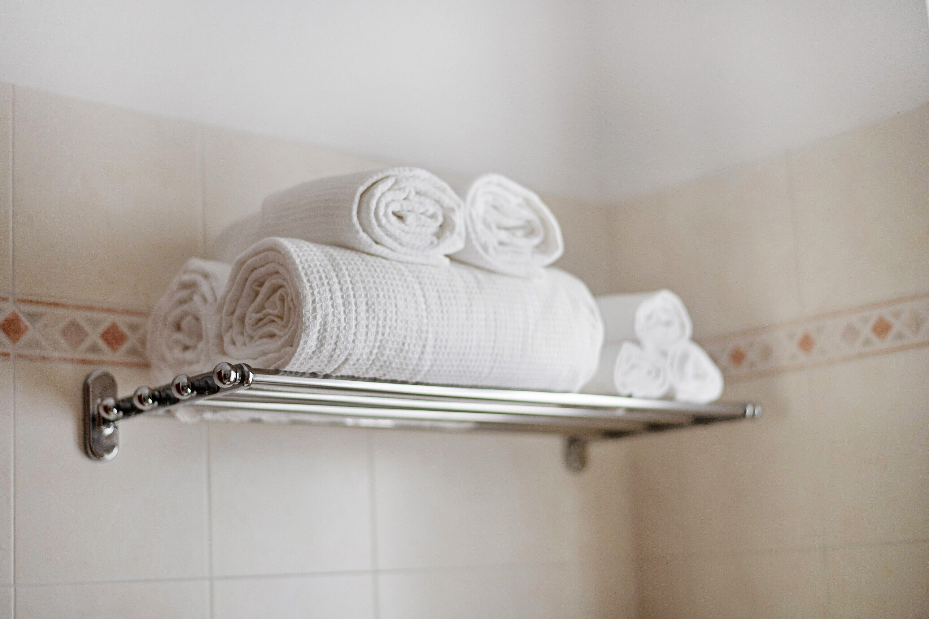 Un bagno con un portasciugamani pieno di asciugamani arrotolati.