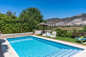 A swimming pool with lounge chairs and a view of a mountainous landscape.