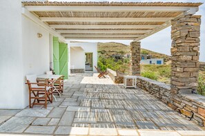 Eine überdachte Terrasse im Freien mit Steinböden, einem Tisch mit Stühlen und einer Steinsäule.