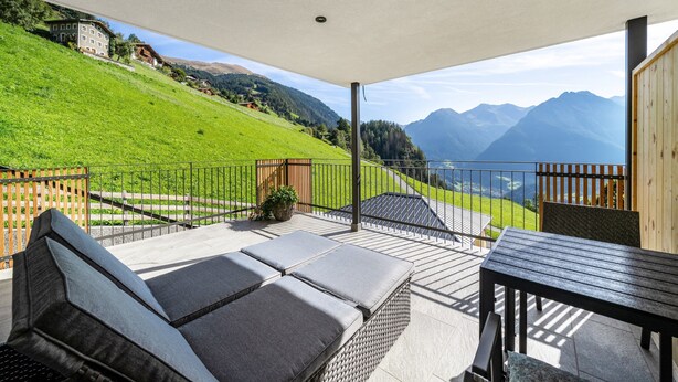 A covered outdoor patio with a view of a green hillside and mountains. - Apartment 'Sunnseitn Lodge Alps' with Mountain View, Private Terrace and Wi-Fi (Moos in Passeier)