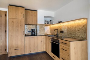 A modern kitchen with wooden cabinets, a stainless steel sink, and a built-in oven.