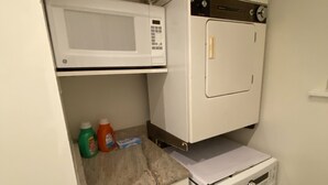 Una lavanderia funzionale con lavatrice, forno a microonde e un piccolo mobiletto.