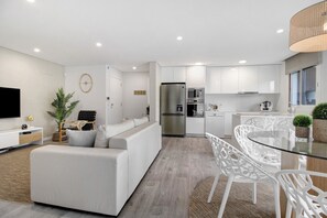 A modern kitchen with white cabinets, a stainless steel refrigerator, and a dining area with a glass table and white chairs. - Apartment "Apúlia" with Shared Pool & Wi-Fi (Apúlia)