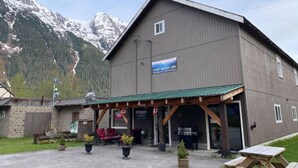 Uma pousada de montanha com placa, área de estar externa e vista para montanhas nevadas.