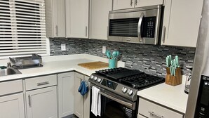 Una cucina moderna con mobili grigi, un forno a microonde in acciaio inossidabile, un piano cottura a gas e un forno integrato.