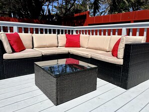A sectional sofa with red cushions on a white deck with a glass coffee table. - Casa Bella (Seaside)