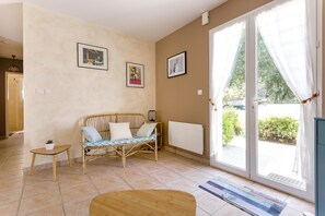 Une pièce comprenant un canapé, une petite table, un radiateur et une porte-fenêtre coulissante donnant sur l’extérieur.
