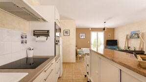 A kitchen with a stove, oven, and a dining area with a chair and table. - Holiday Home "Begognias" with Private Terrace (LE CHATEAU-D'OLERON)