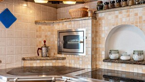 A kitchen with a built-in oven, a stove, and a shelf with jars.