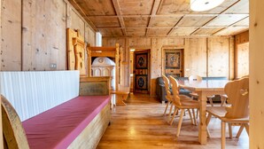 A wooden interior with a bed, a dining table, and chairs.