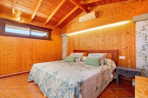 Une chambre à coucher aux murs lambrissés, avec un grand lit, une table de chevet et une fenêtre.