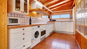 A kitchen with white cabinets, a microwave, a washing machine, and a coffee maker.
