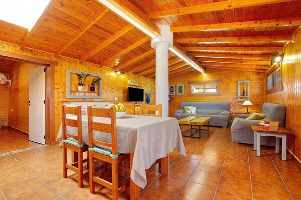 Un interior de madera con una mesa de comedor, sillas, un sofá y un televisor.