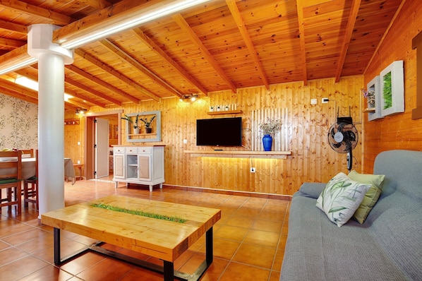 Un intérieur en bois avec un canapé, une table, un téléviseur et un ventilateur.