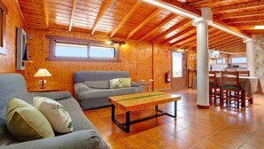 A wooden interior with a sofa, a table, and a dining area.