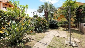Ein Garten mit einer Pergola, Palmen und verschiedenen Pflanzen.