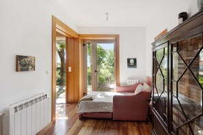 A bedroom with a bed, a sofa, a radiator, and a cabinet.