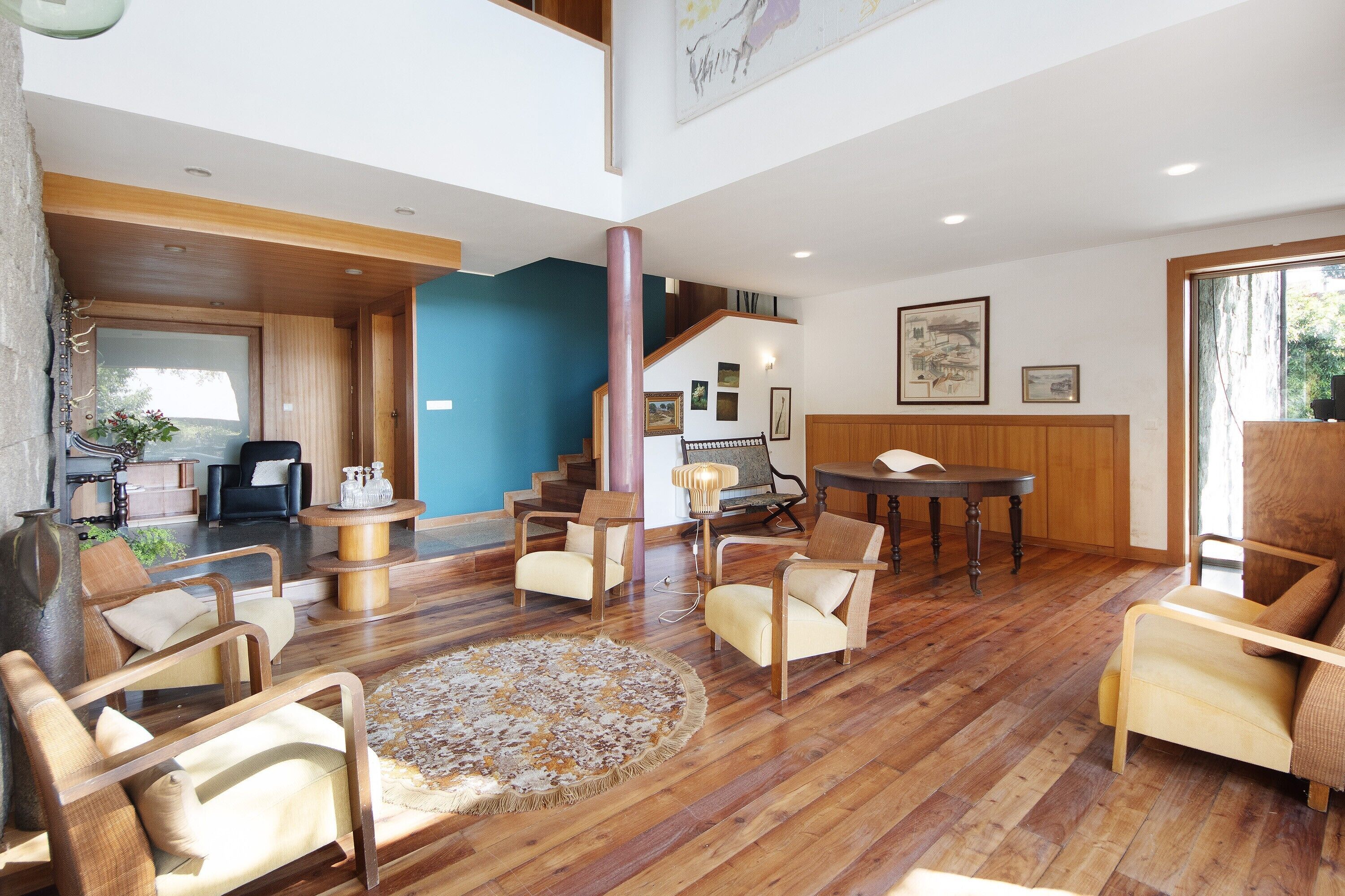 A spacious living area with wooden flooring, multiple seating arrangements, and a staircase leading to an upper level.