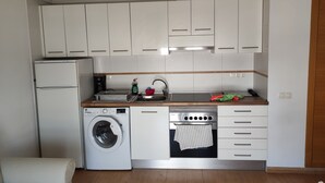 A compact kitchen with a washing machine, a built-in oven, and a coffee maker. - Apartment "Jorro" with Shared Pool & Terrace (El Verger)