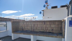 A rooftop terrace with a white wall, a brick wall, and a metal fence. - Apartment "Jorro" with Shared Pool & Terrace (El Verger)