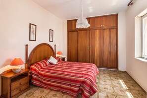 Une chambre à coucher avec un lit, une armoire en bois et une table de chevet avec une lampe.