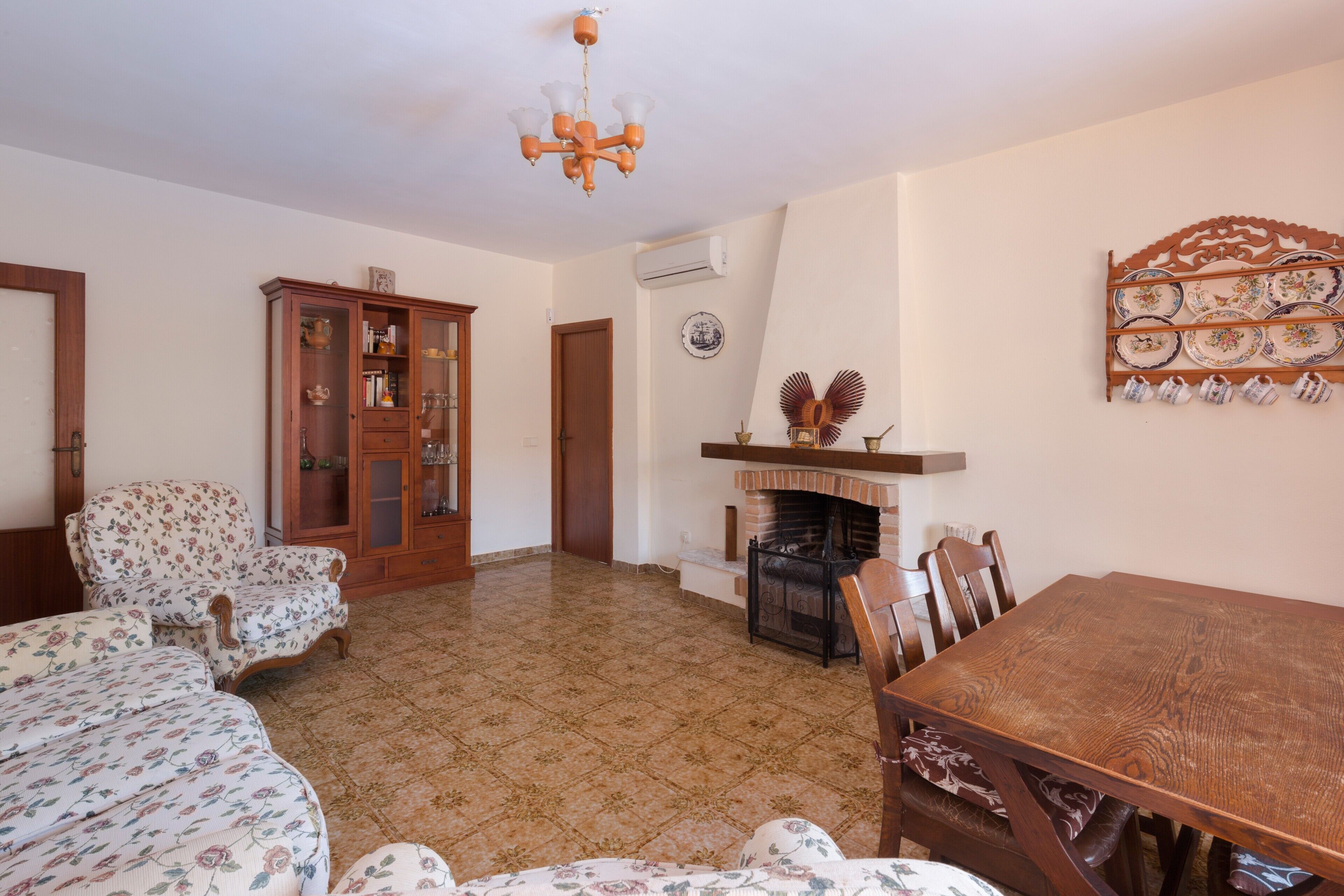 A living room with a fireplace, a dining table, and floral-patterned furniture.