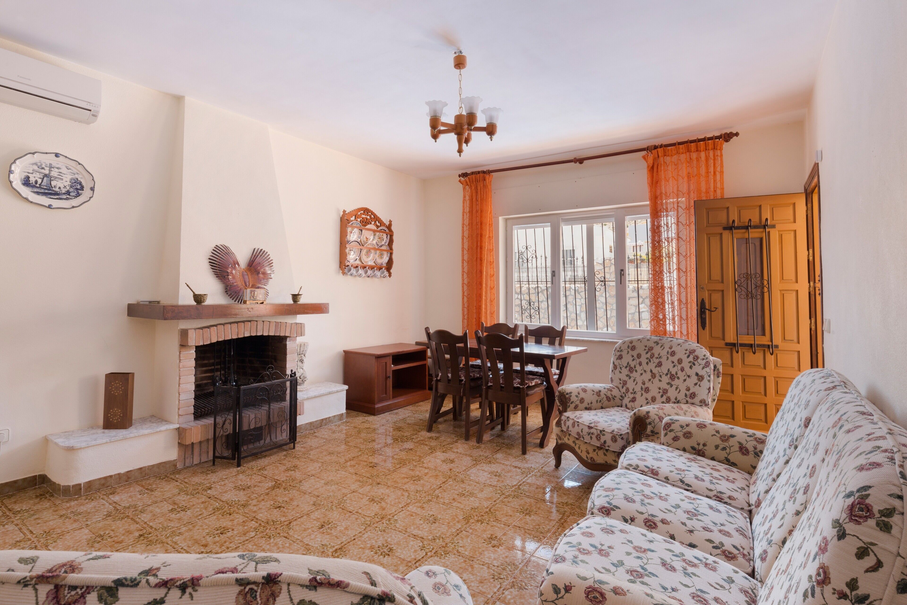 Una sala de estar con chimenea, una mesa de comedor con sillas, un sofá y una ventana con cortinas.