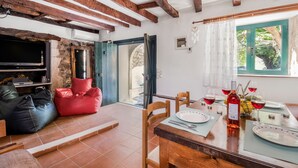 Una habitación con una mesa de comedor preparada para dos personas, un televisor y una zona de estar acogedora con pufs.