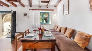 Comedor con una mesa de madera preparada para cuatro personas, un sofá marrón y una ventana con vistas a zonas verdes.