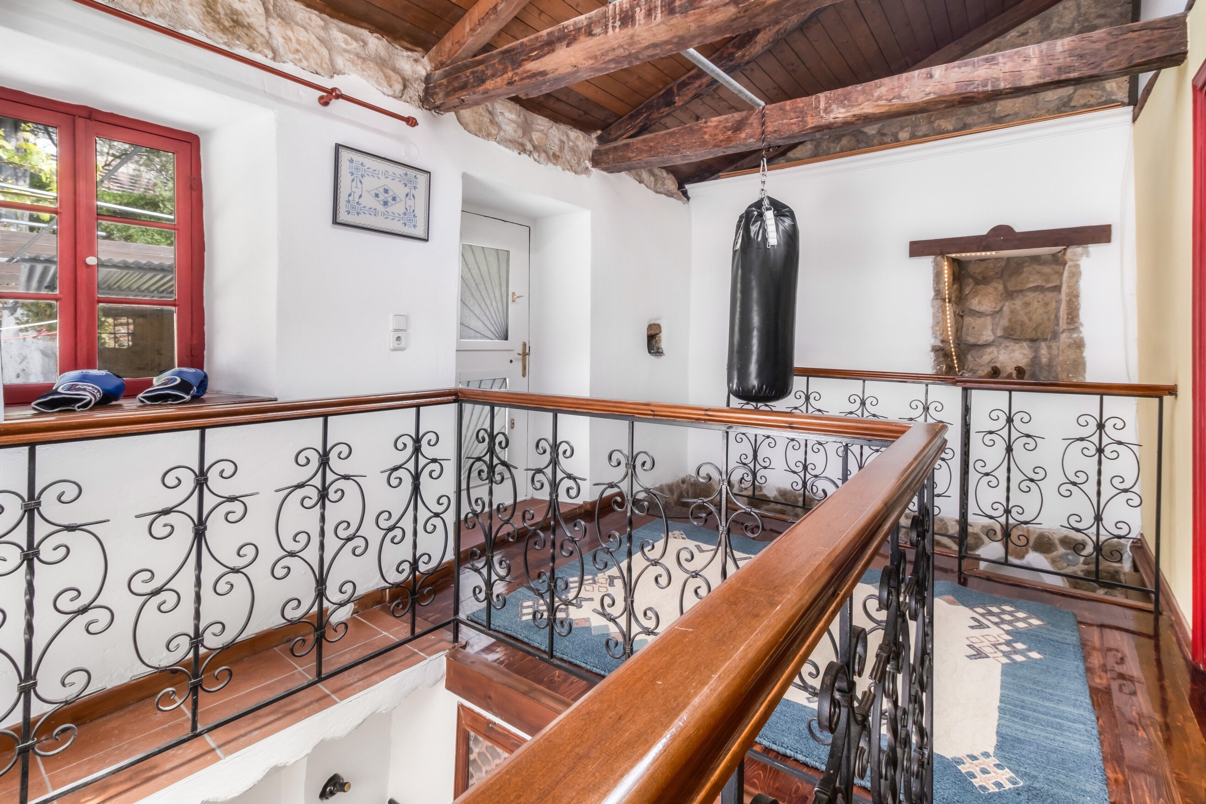 Un escalier en bois avec des rampes en métal, un sac de frappe et une porte rouge.