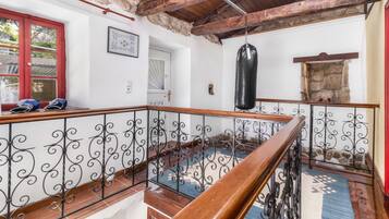 Un escalier en bois avec des rampes en métal, un sac de frappe et une porte rouge.