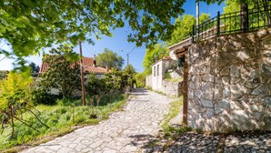 Un sendero de piedra que conduce a un edificio rústico con muro de piedra y cerca de metal.