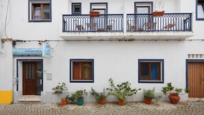 Um edifício de dois andares com uma placa indicando 'Casa De Hospedales' e diversos vasos de plantas ao longo do andar térreo.