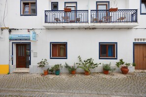 Un bâtiment à deux étages, avec une enseigne indiquant « Casa De Hospedales », et de nombreuses plantes en pot disposées le long du rez-de-chaussée.
