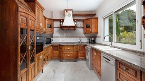 Una cocina con armarios de madera, encimeras de granito, horno empotrado y ventana con vistas a zonas verdes.