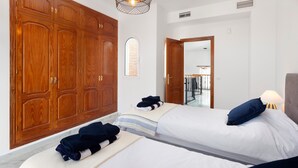 Habitación de hotel con dos camas, armario de madera, una ventana pequeña y una puerta que da a un balcón.