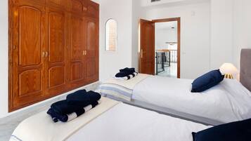 Een hotelkamer met twee bedden, een houten kledingkast, een klein raam en een deur naar een balkon.