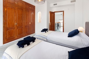 Une chambre d’hôtel avec deux lits, une armoire en bois, une petite fenêtre et une porte donnant sur un balcon.