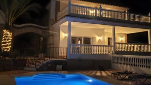 Un edificio de dos plantas con piscina, chimenea de piedra y balcón con barandilla.