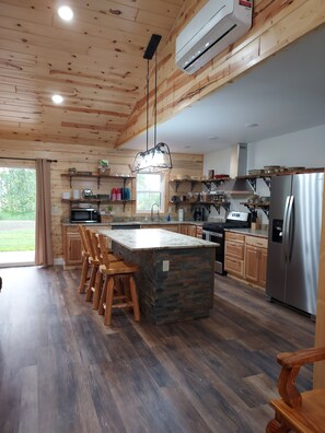 A modern kitchen with wooden cabinetry, a central island, and a stainless steel refrigerator. - Finlayson log cabin on 10 acres (Finlayson)