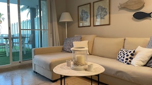 A living room with a sofa, a coffee table, a lamp, and artwork on the wall. - Apartment 'Residencial Mar De Denia 2' with Sea View, Wi-Fi and Air Conditioning (Denia)