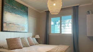 A bedroom with a bed, a window with curtains, a lamp, and a painting on the wall. - Apartment 'Residencial Mar De Denia 2' with Sea View, Wi-Fi and Air Conditioning (Denia)